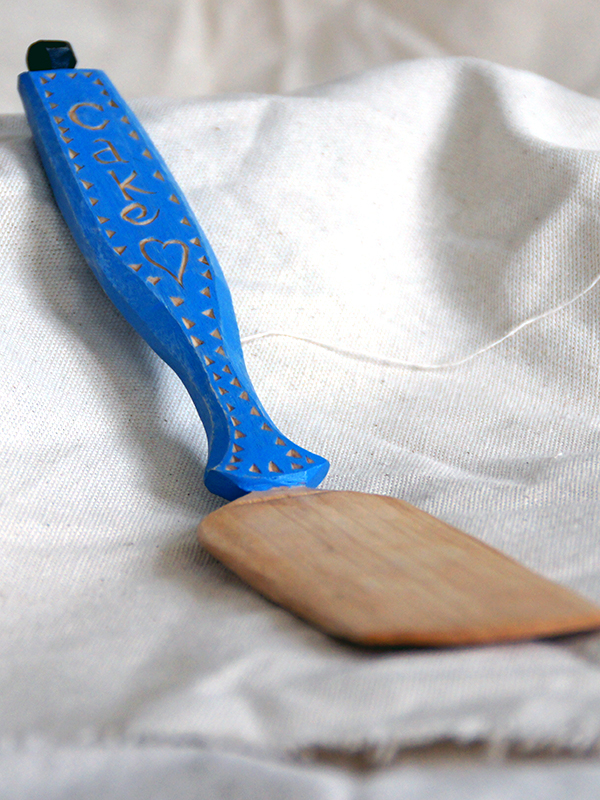 a wooden steam bent cake server, the handle is chip-carved and decorated with artists oil paint